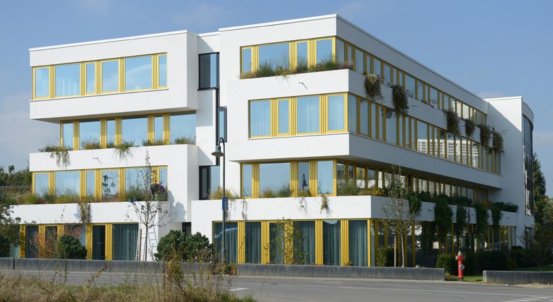 Weiße Pflegeresidenz mit Terrassen und gelben Fensterrahmen