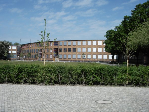 Klinkerbau der Max-Taut-Schule hinter einer Hecke