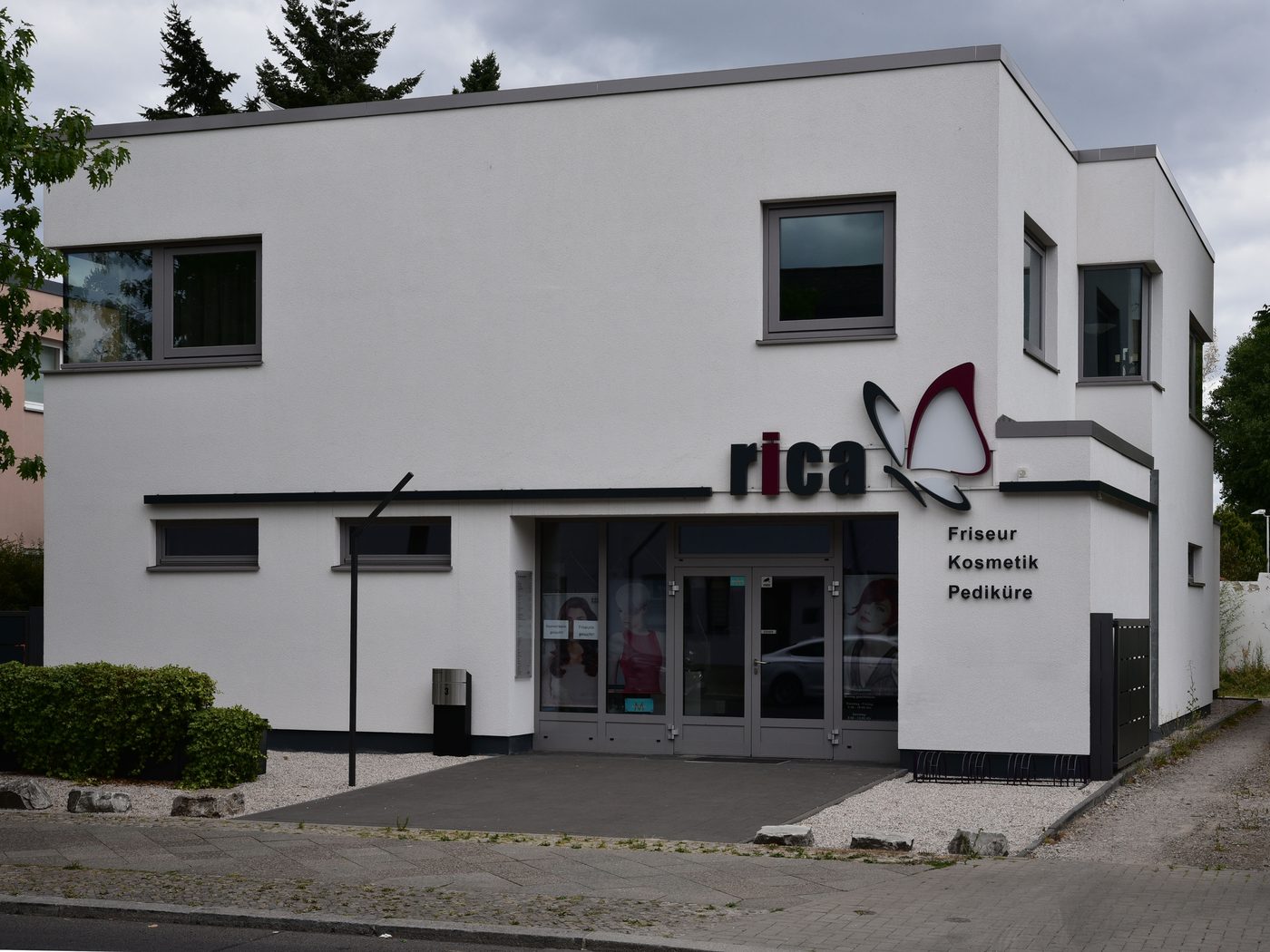 Weißer Flachdachbau mit Gewerbeeinheit im Erdgeschoss